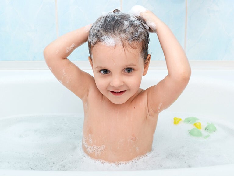 Este niño pequeño se está lavando la cabeza con champú. Está en la bañera y tiene algunos juguetes en el agua.