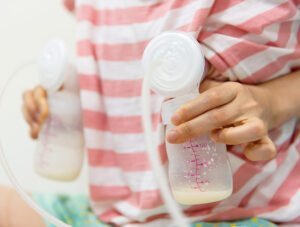 Esta madre tiene un biberón con leche en cada mano. Parece que sus hijos no se lo han terminado del todo.