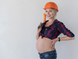 Esta embarazada tiene un rodillo de pintar paredes en su mano.