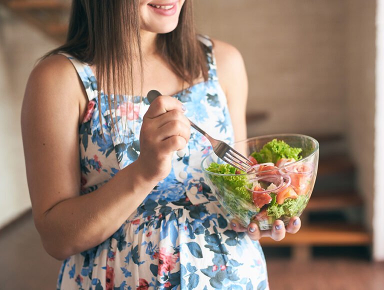 Esta mujer embarazada está disfrutando de una deliciosa ensalada con un poco de aceite y vinagre. parece que se le ha entojado.