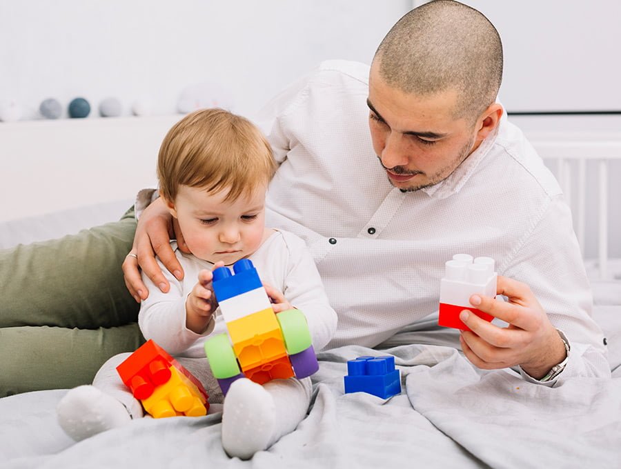 Este padre está jugando con su hijo y sus juguetes de plástico. Parece que se divierten.