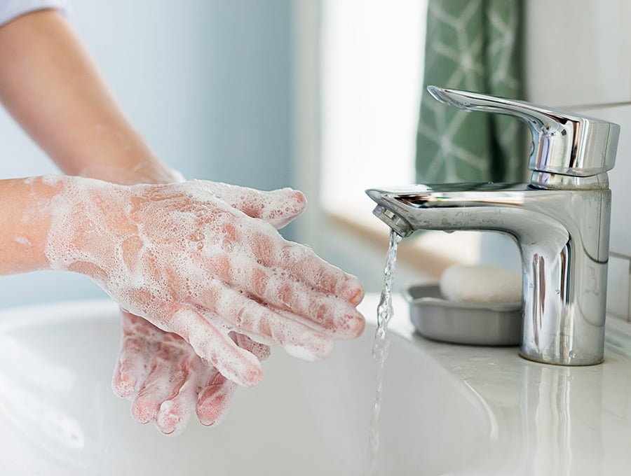 Una persona se está lavando las manos con jabón en el lavabo del cuarto de baño.