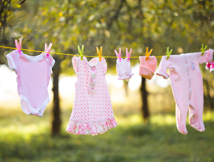 Prendas de ropa de un bebé colgadas en una cuerda en el jardín.