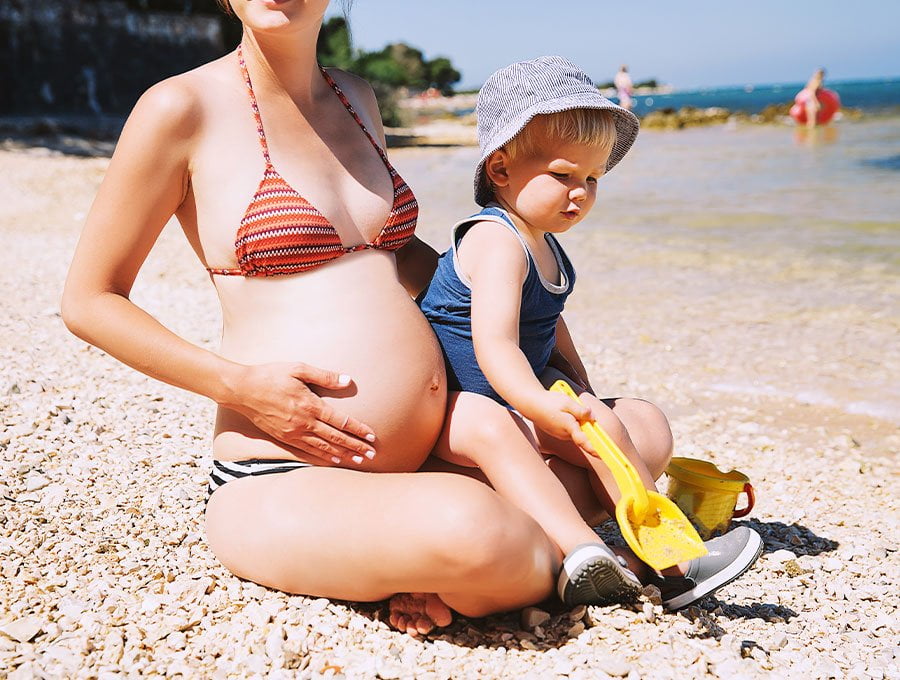 Esta madre está con su hijo mayor en la playa. Está embarazada y el pequeño tendrá una hermanita.