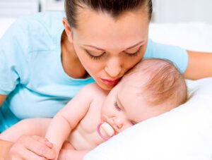Esta madre le da un besito en la mejilla a su bebé mientras está dormido.