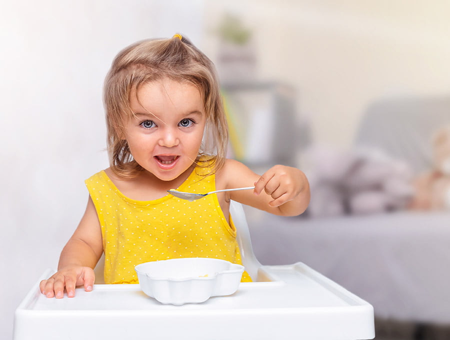 Esta niña pequeña se está tomando un plato de cereales con leche.