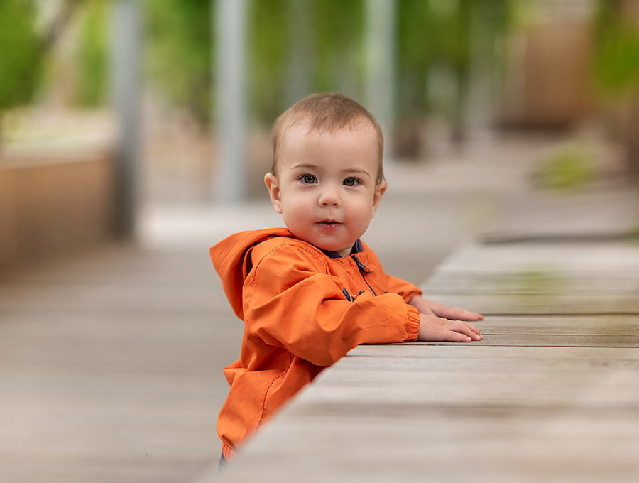 Este niño lleva un chubasquero de color naranja. Está haciendo el cafre en el patio exterior de su casa.