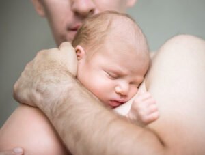 Padre tiene en sus brazos a su recién nacido. Parece que lo quiere mucho.