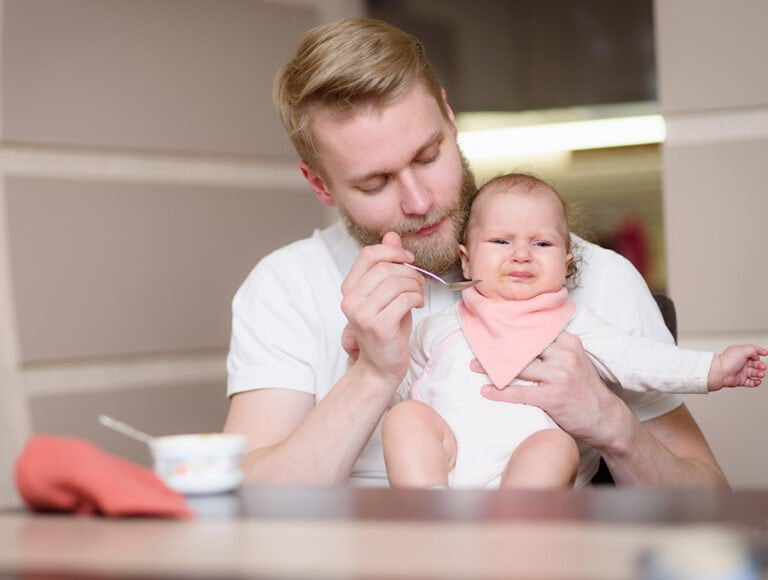 Este padre le está dando puré al bebé, aunque parece que no le está gustando su sabor.