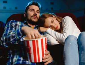 Esta pareja está viendo una película en el cine. Están comiendo palomitas.