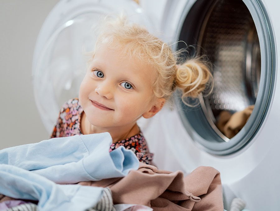 Niña pequeña junto a la ropa del lavadero.
