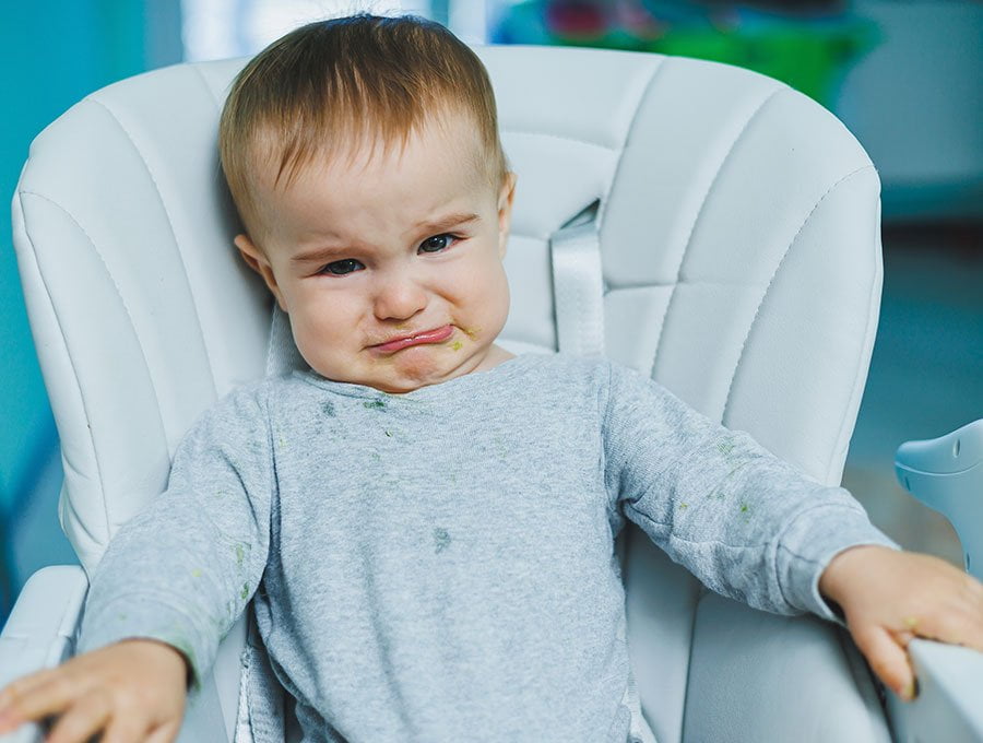 El bebé está llorando en la trona porque no quiere comer.