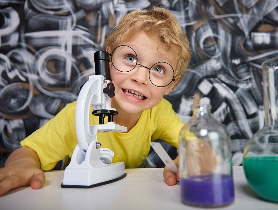 Este niño se divierte con el microscopio en su dormitorio.